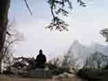 Daoist Monk at Mt Huashan in meditation at mountain overlook
